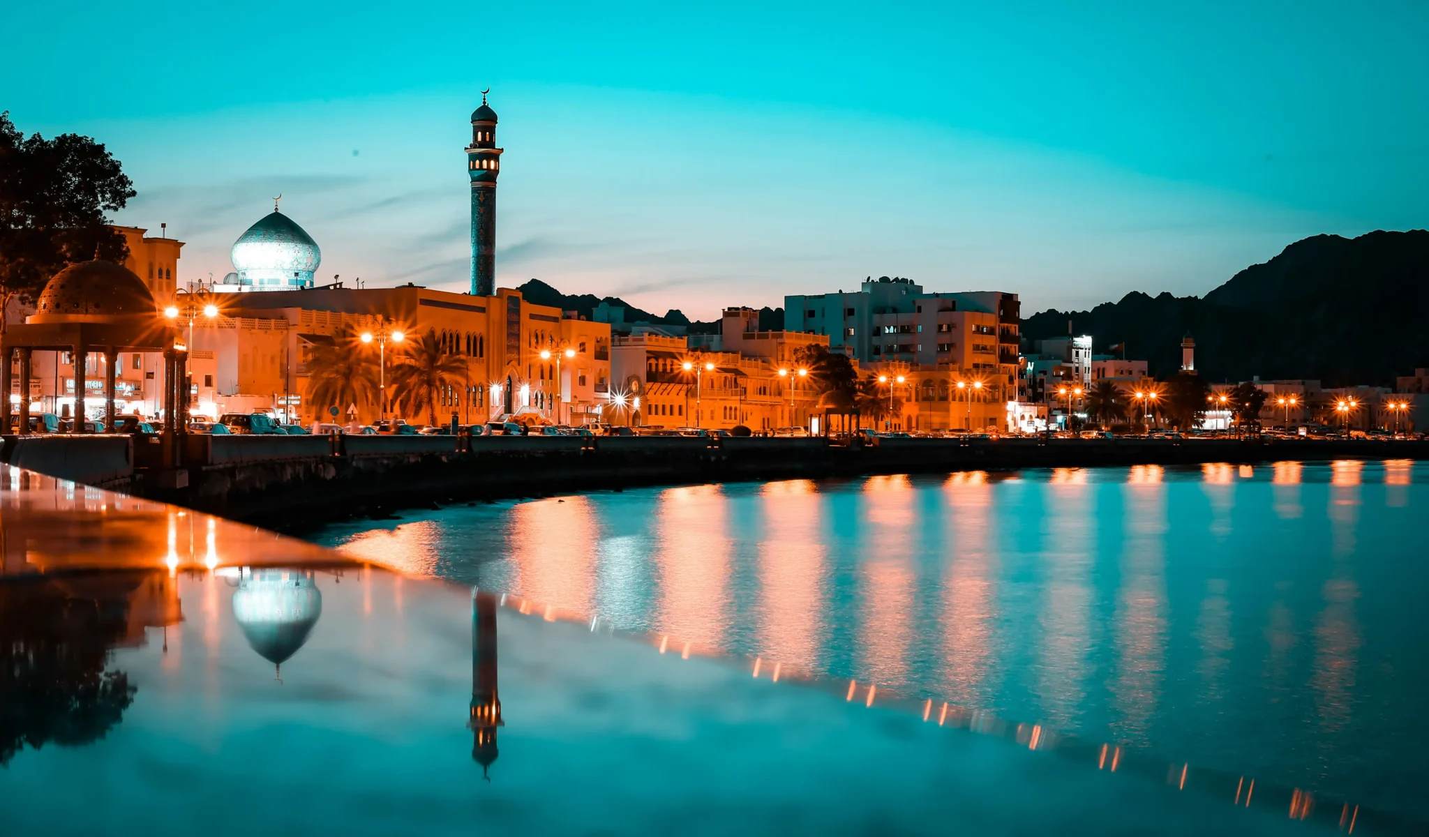 Muscat waterfront and mosque reflected in the bay at dusk