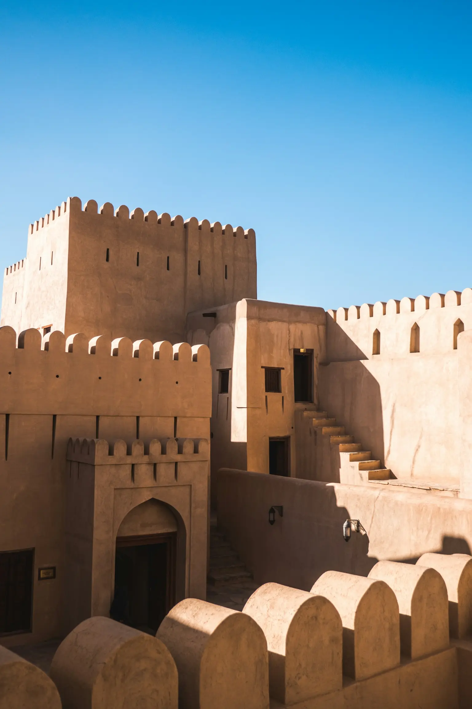 Sand-coloured Omani fort with crenellated towers